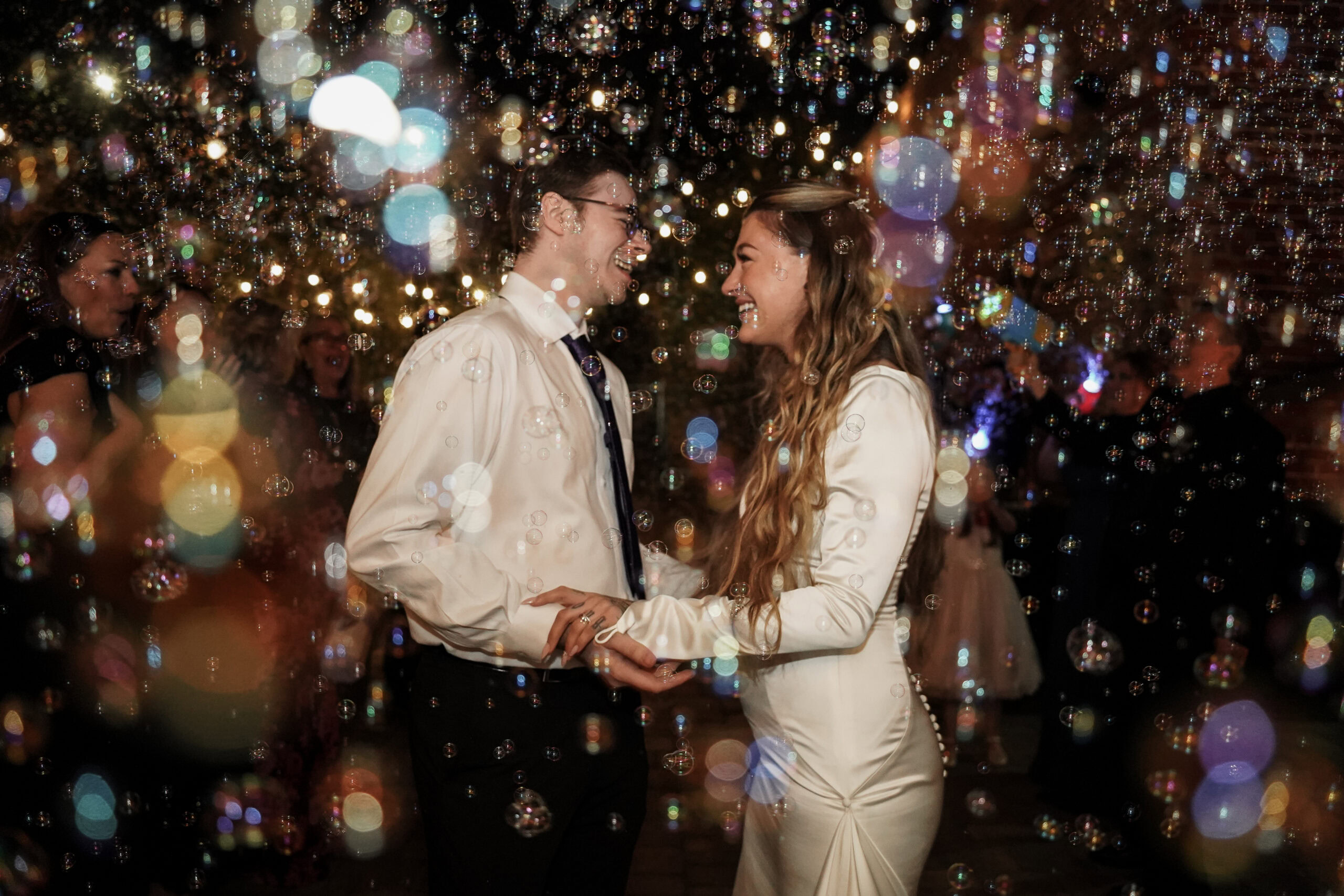 Wedding dance at night with sparkling lights and joyful couple.